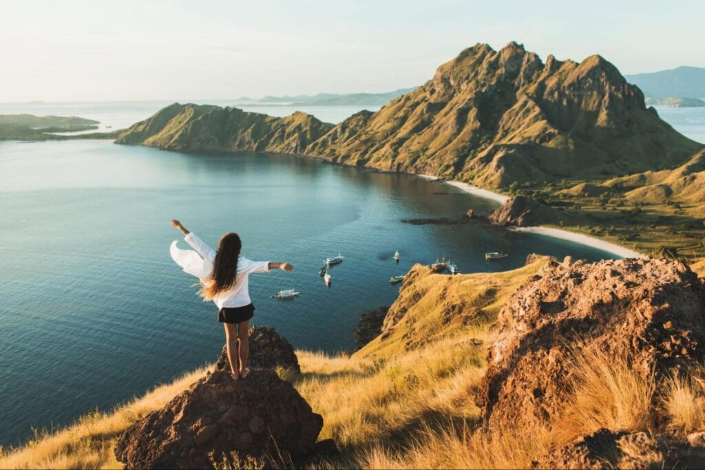 Panorama Pulau Padar dilihat dari puncak bukit saat trekking dengan kapal wisata di bawah