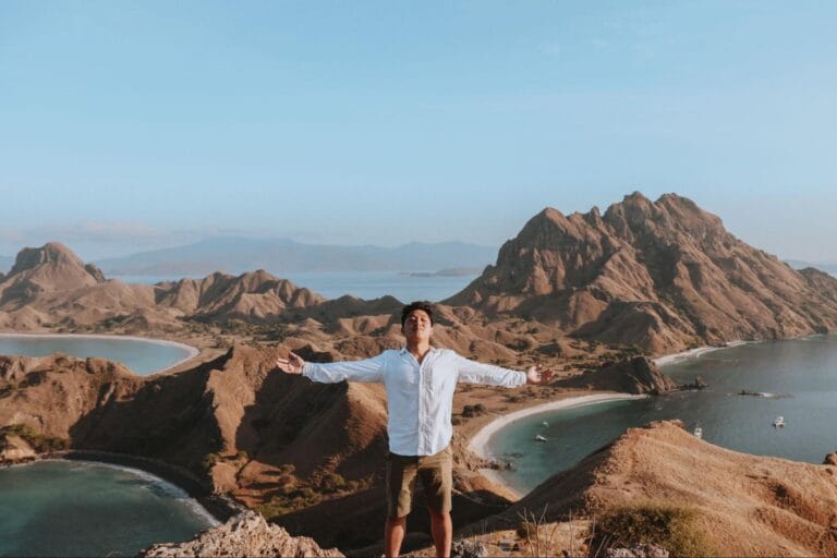 Wisatawan berdiri di puncak Pulau Padar Labuan Bajo dengan panorama tiga teluk saat trekking