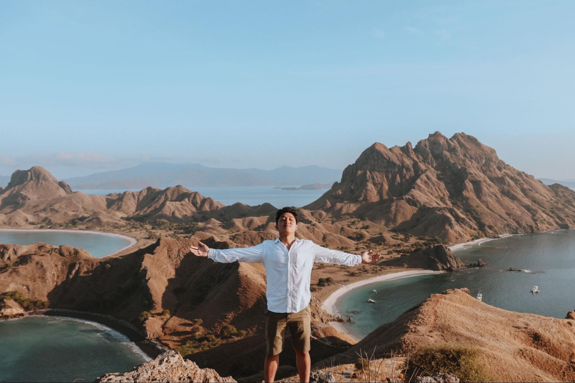 Wisatawan berdiri di puncak Pulau Padar Labuan Bajo dengan panorama tiga teluk saat trekking