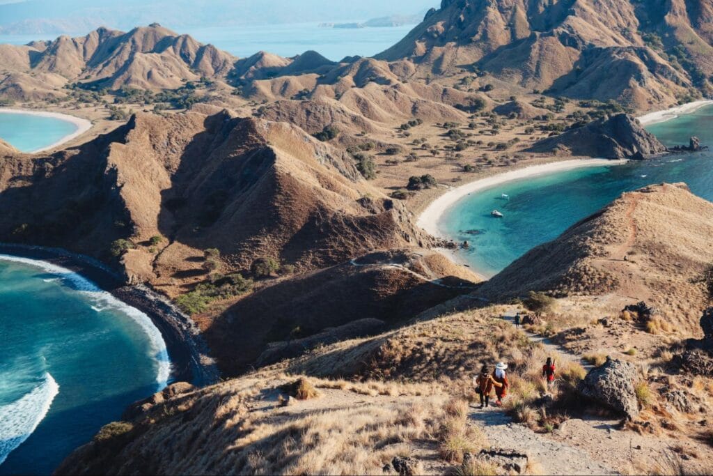 Wisatawan berjalan di jalur trekking Pulau Padar dengan medan curam dan savana terbuka menuju puncak bukit