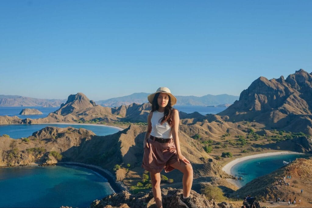 Puncak bukit Pulau Padar atau hilltop viewpoint sebagai spot foto ikonik dengan latar tiga teluk dan bukit savana