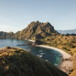 Spot foto terbaik di Pulau Padar dengan panorama bukit savana dan teluk berwarna yang terlihat dari viewpoint puncak