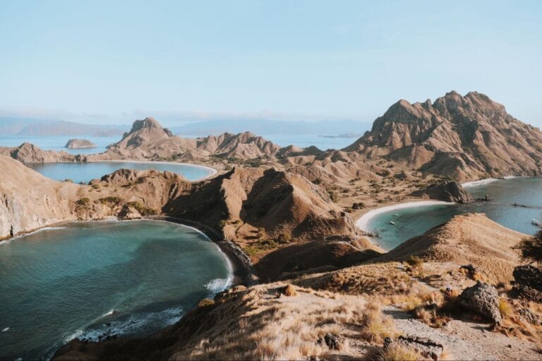 pemandangan pulau padar pagi vs siang hari dengan bukit savana dan teluk melengkung dari atas