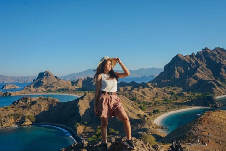 solo traveler di pulau padar menikmati pemandangan bukit savana dan tiga teluk dari puncak