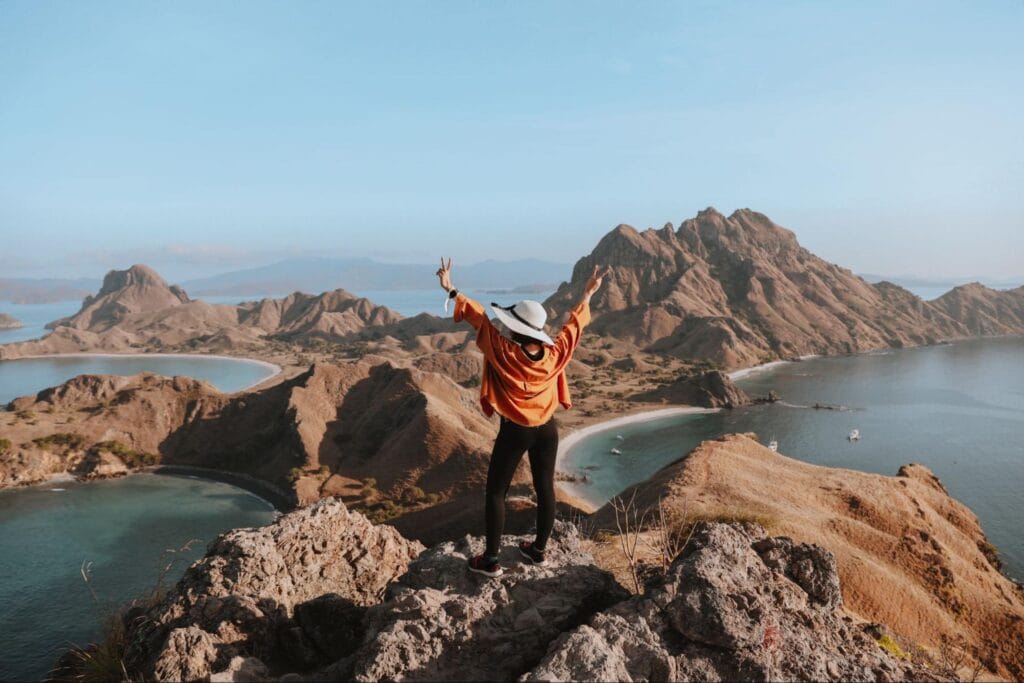 wisatawan menikmati pemandangan pulau padar saat sore hari dengan cahaya sunset dramatis dari puncak bukit